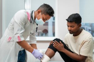Doctor applying bandage to patient’s knee injury during orthopedic treatment